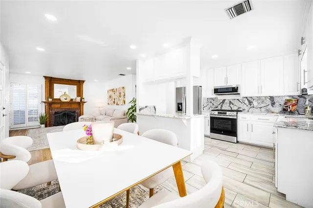 a kitchen with stainless steel appliances kitchen island granite countertop a stove a sink a dining table and chairs