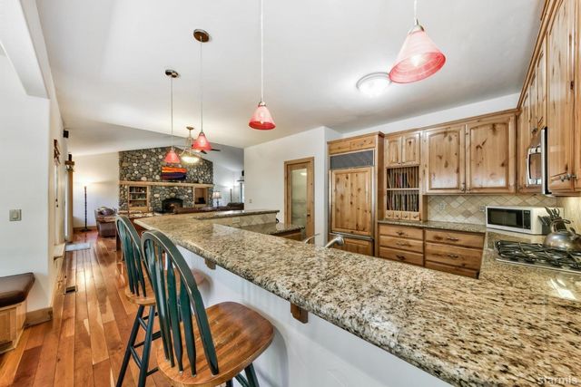 a kitchen with stainless steel appliances kitchen island granite countertop a stove top oven a sink a dining table and chairs with wooden floor