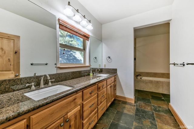 a bathroom with a granite countertop sink and a large mirror