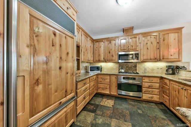 a kitchen with stainless steel appliances granite countertop a refrigerator oven a sink dishwasher and white cabinets with wooden floor