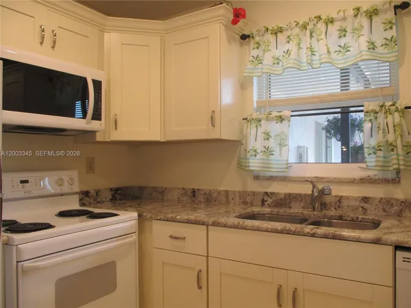 a kitchen with granite countertop white cabinets and stainless steel appliances