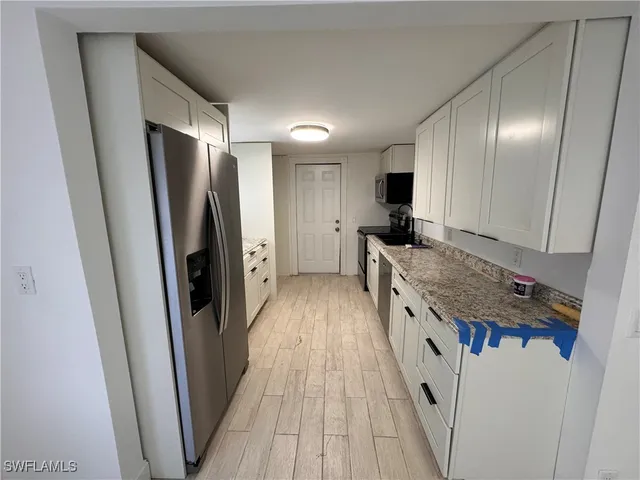 a kitchen with sink a refrigerator and wooden floor