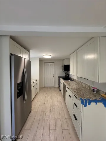 a large kitchen with a center island wooden floor stainless steel appliances and cabinets