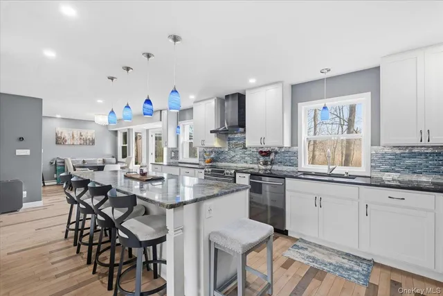a kitchen with granite countertop a dining table chairs cabinets and stainless steel appliances