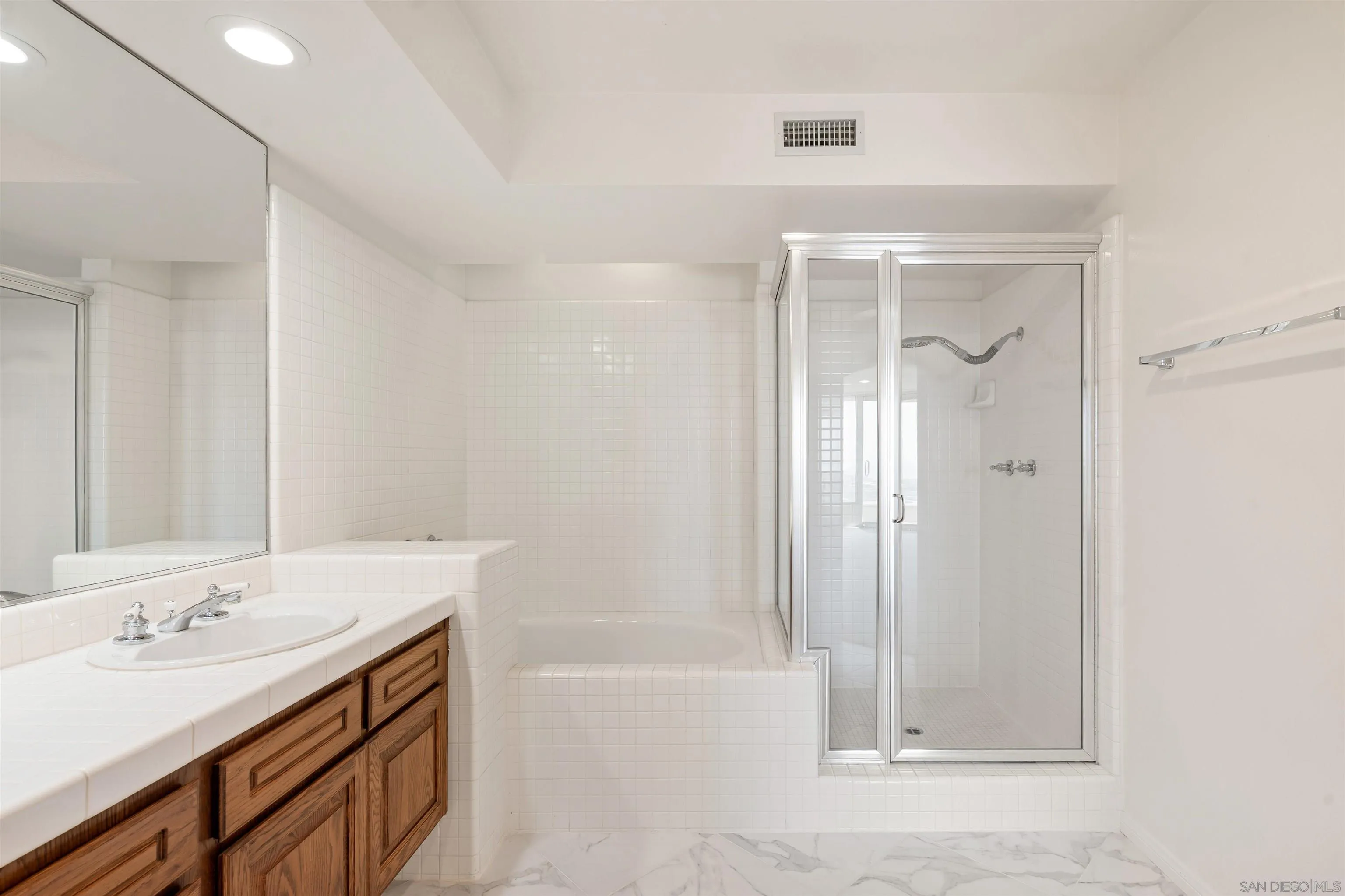 13286 Ocean Vista Road San Diego, CA 92130 - Photo 30 of 66 a bathroom with a sink a mirror and a bathtub