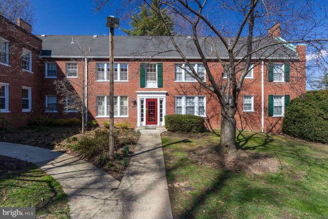 a view of a brick house next to a yard with potted plants