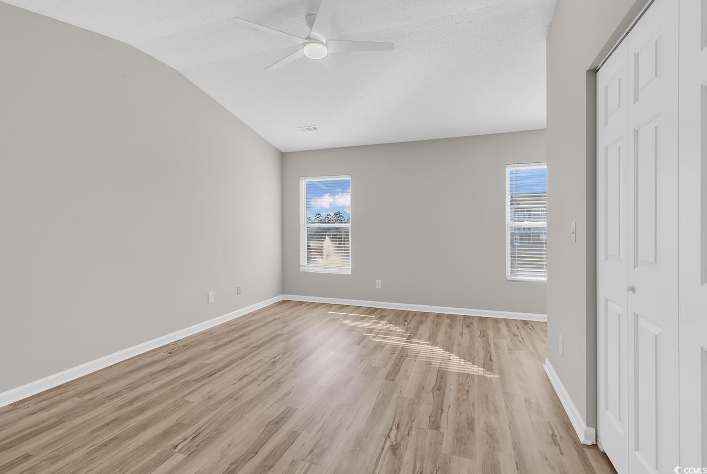 308 Kiskadee Loop, Unit E Conway, SC 29526 - Photo 17 of 36 Unfurnished bedroom featuring a closet, light wood-style flooring, a ceiling fan, vaulted ceiling, and a textured ceiling