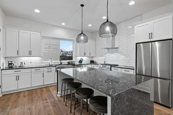 a kitchen with stainless steel appliances granite countertop a sink a stove and a refrigerator