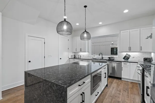 a kitchen with stainless steel appliances granite countertop a sink a stove and a wooden floors
