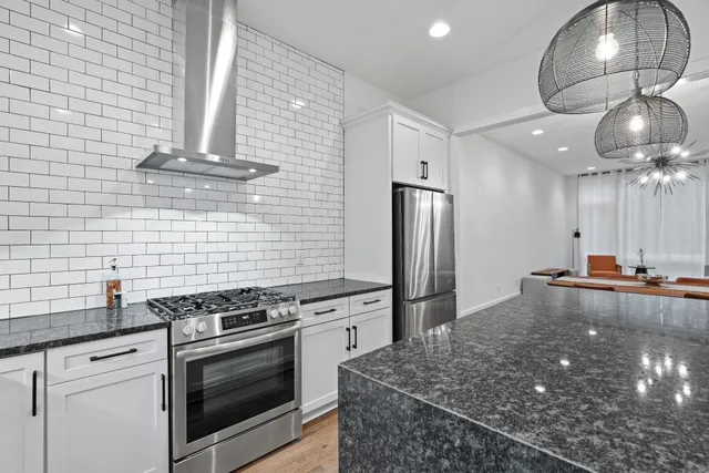 a kitchen with stainless steel appliances granite countertop a stove a sink and a refrigerator