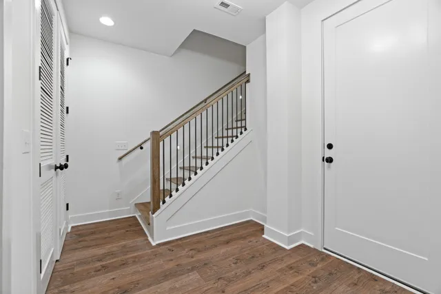 a view of a hallway with entryway and bedroom with wooden floor