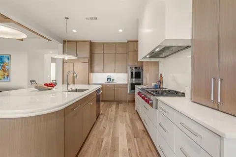 a large kitchen with stainless steel appliances granite countertop a lot of cabinets and wooden floor