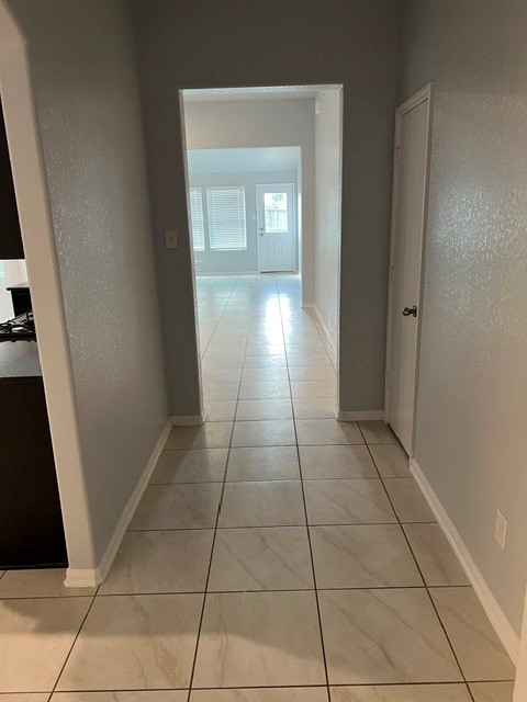 18303 Ranch View Trail Houston, TX 77073 - Photo 2 of 19 Bright and spacious hallway with elegant tile flooring leads to a sunlit living area, featuring large windows and a door to the outside.