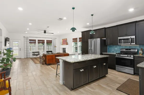 a kitchen with kitchen island granite countertop stainless steel appliances a sink stove and refrigerator