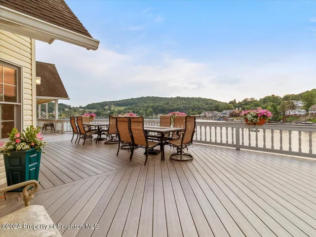 a view of a roof deck with table and chairs a barbeque with wooden floor and fence