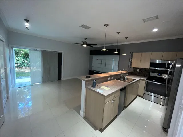 a living room with stainless steel appliances kitchen island a sink and a refrigerator