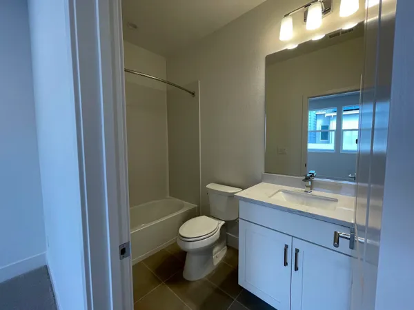 a bathroom with a granite countertop toilet a sink and a mirror