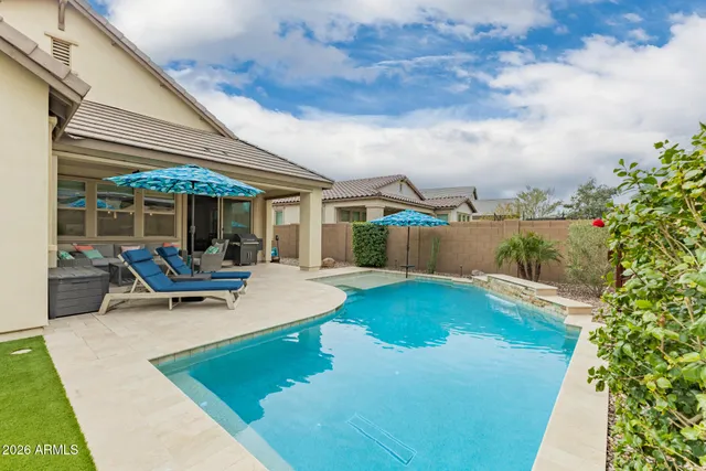 a view of a swimming pool with chairs in front of house