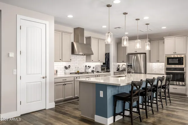 a kitchen with stainless steel appliances kitchen island granite countertop a sink a stove a dining table chairs and view living room