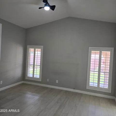 an empty room with wooden floor cabinet and windows