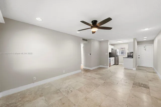 a view of a livingroom with a ceiling fan and kitchen space