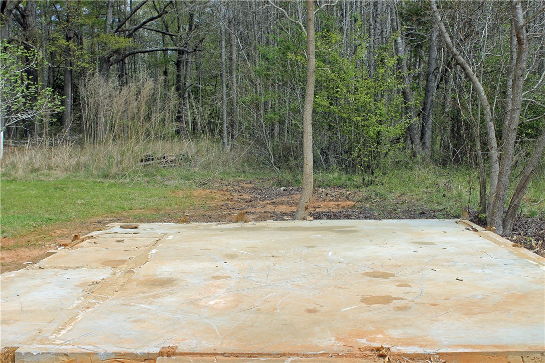 1007 O Neal Street Belton, SC 29627 - Photo 19 of 25 A clear building pad offers a blank canvas for new construction, set against a backdrop of mature trees.