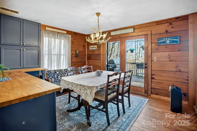 a dining room with wooden floor a chandelier a wooden table and chairs