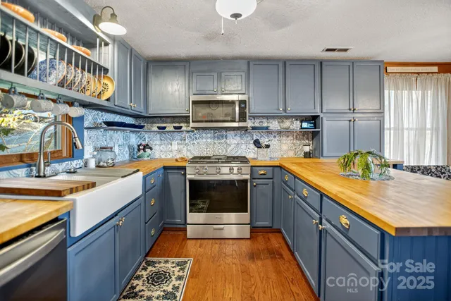 a kitchen with stainless steel appliances granite countertop a stove a sink and a microwave