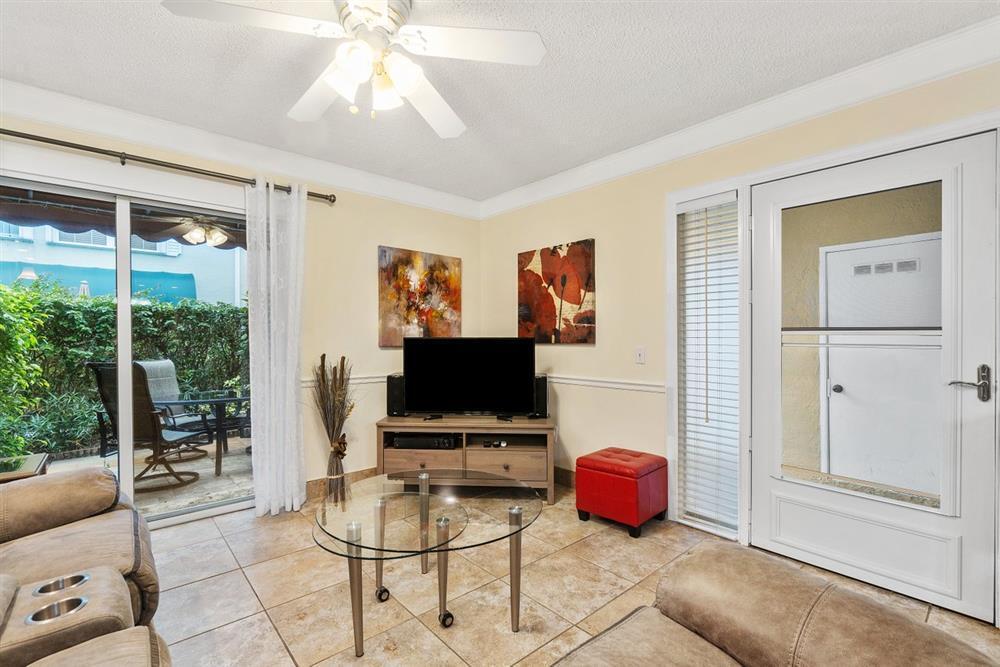 a living room with furniture a flat screen tv and a floor to ceiling window