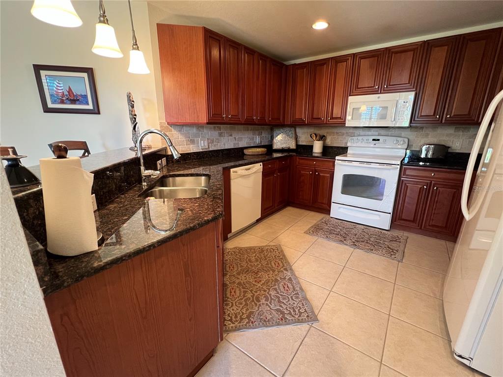 240 West End Drive, Unit 611 Punta Gorda, FL 33950 - Photo 11 of 19 a kitchen with granite countertop wooden cabinets and stainless steel appliances