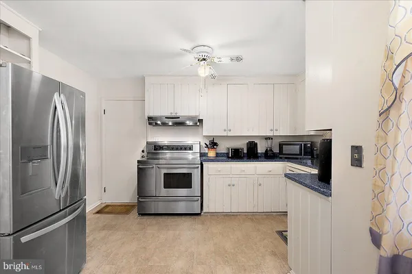 a kitchen with a refrigerator a sink and dishwasher a stove top oven with white cabinets