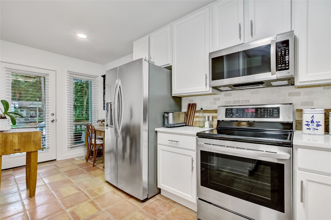 3426 Sea Marsh Road Fernandina Beach, FL 32034 - Photo 9 of 65 a kitchen with stainless steel appliances white cabinets a stove a microwave and a refrigerator