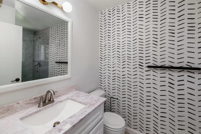 a bathroom with a granite countertop toilet a sink and a mirror