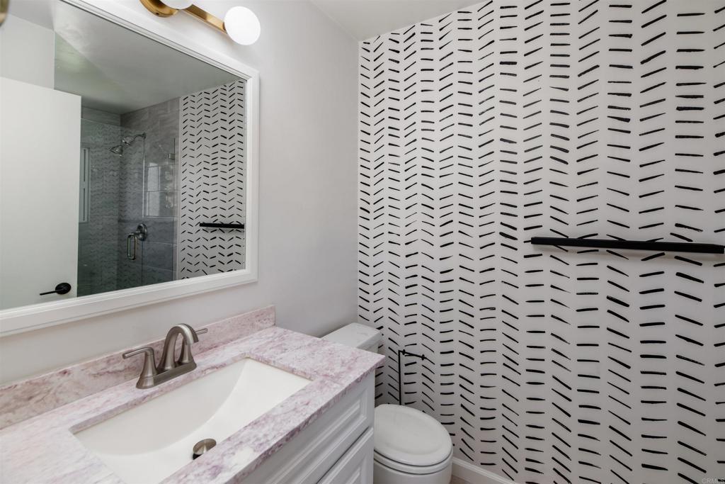 2349 Altisma Way, Unit B Carlsbad, CA 92009 - Photo 14 of 25 a bathroom with a granite countertop toilet a sink and a mirror