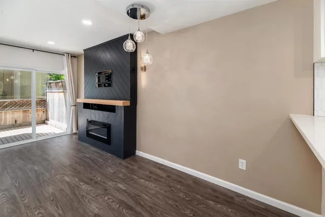an empty room with wooden floor a fireplace and windows