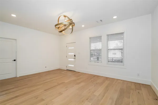 a view of an empty room with a window and wooden floor