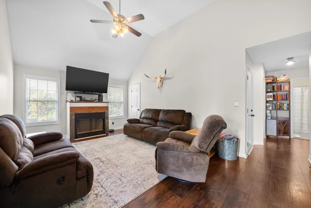 a living room with furniture a fireplace a flat screen tv and wooden floor