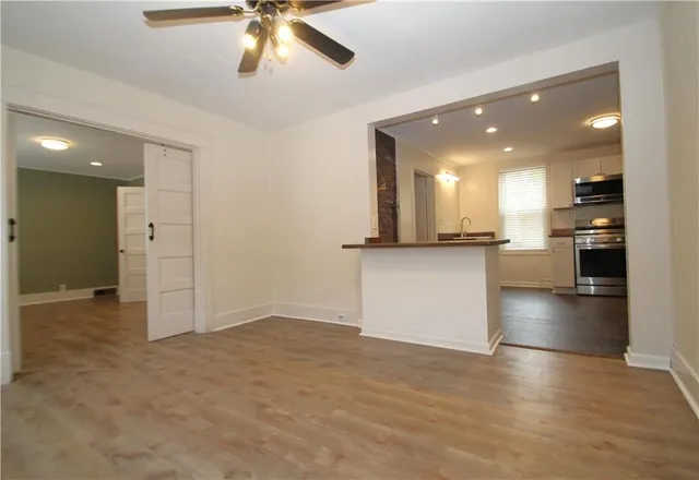 an empty room with wooden floor and kitchen view