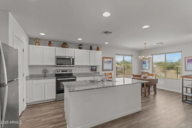 a kitchen with stainless steel appliances kitchen island granite countertop a stove refrigerator and cabinets