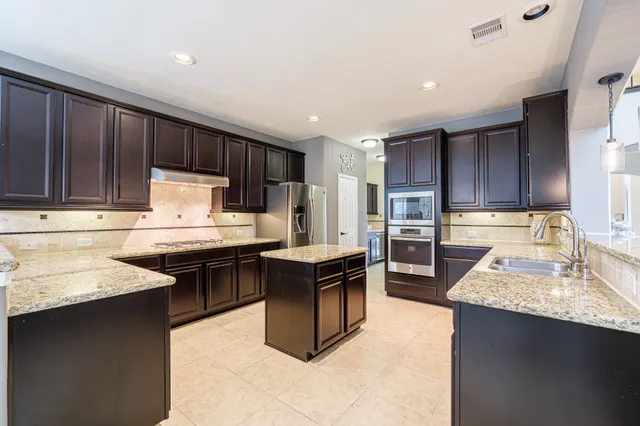a kitchen with granite countertop wooden cabinets a stove top oven a sink and dishwasher
