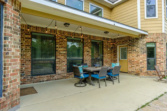 a patio with a table and chairs and potted plants