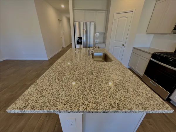 a kitchen with granite countertop a refrigerator and a sink