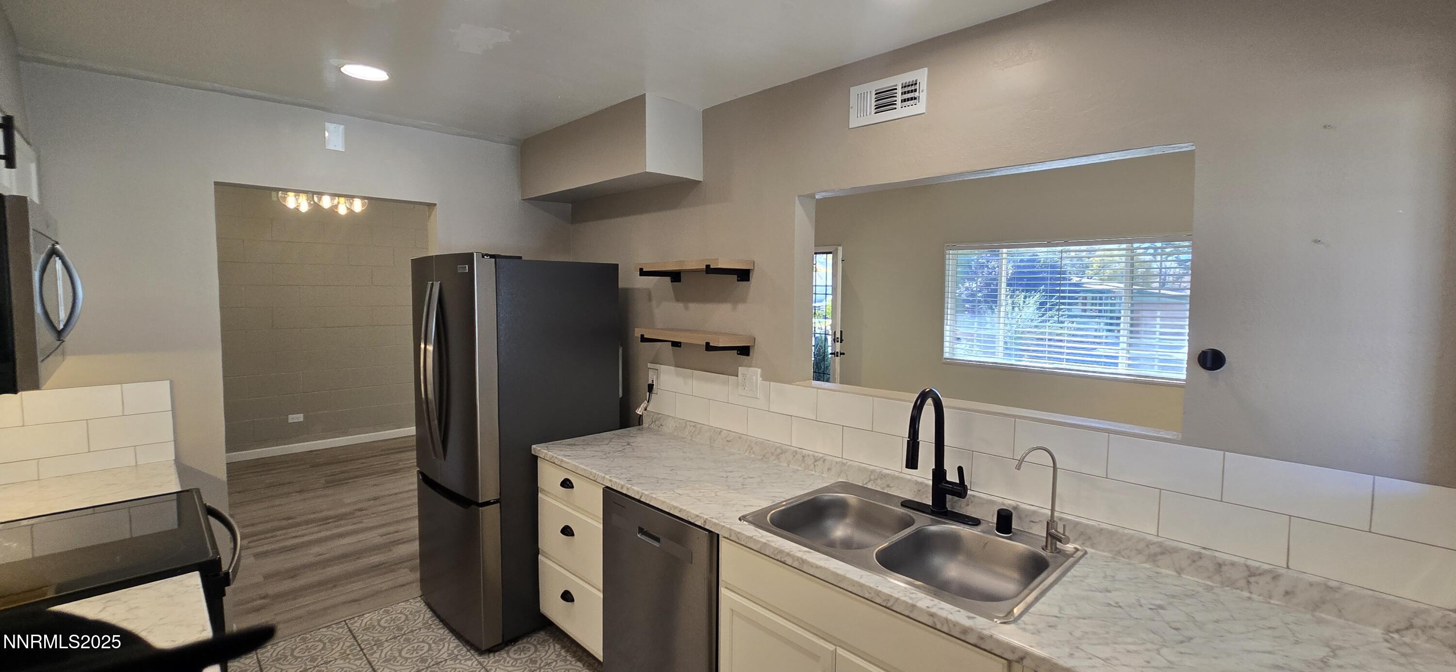 13562 Mt Baldy Street Reno, NV 89506 - Photo 3 of 9 a kitchen with stainless steel appliances granite countertop a sink and a refrigerator