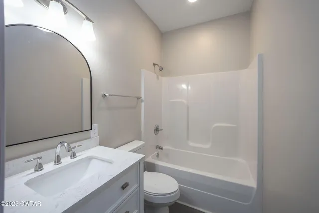 a bathroom with a bathtub shower sink vanity mirror and toilet