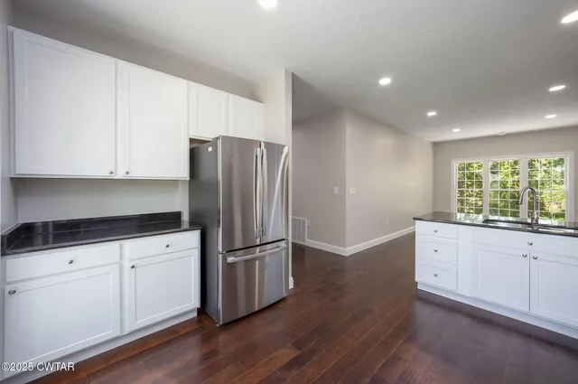a kitchen with granite countertop white cabinets white stainless steel appliances and wooden floors