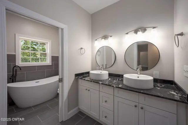 a spacious bathroom with a granite countertop sink mirror and bathtub