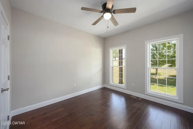 a view of a big room with wooden floor and windows