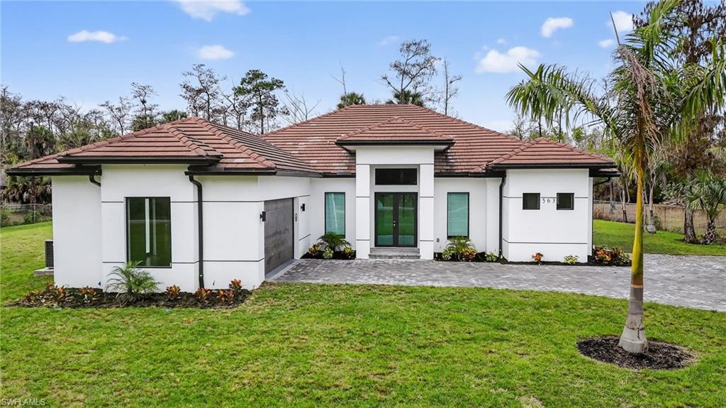 563 15th Street Northwest Naples, FL 34120 - Photo 2 of 33 Back of house featuring stucco siding, a tiled roof, and an attached garage