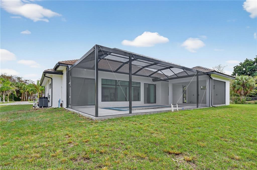 563 15th Street Northwest Naples, FL 34120 - Photo 29 of 33 Rear view of house with a lanai, a yard, a sunroom, stucco siding, and a swimming pool