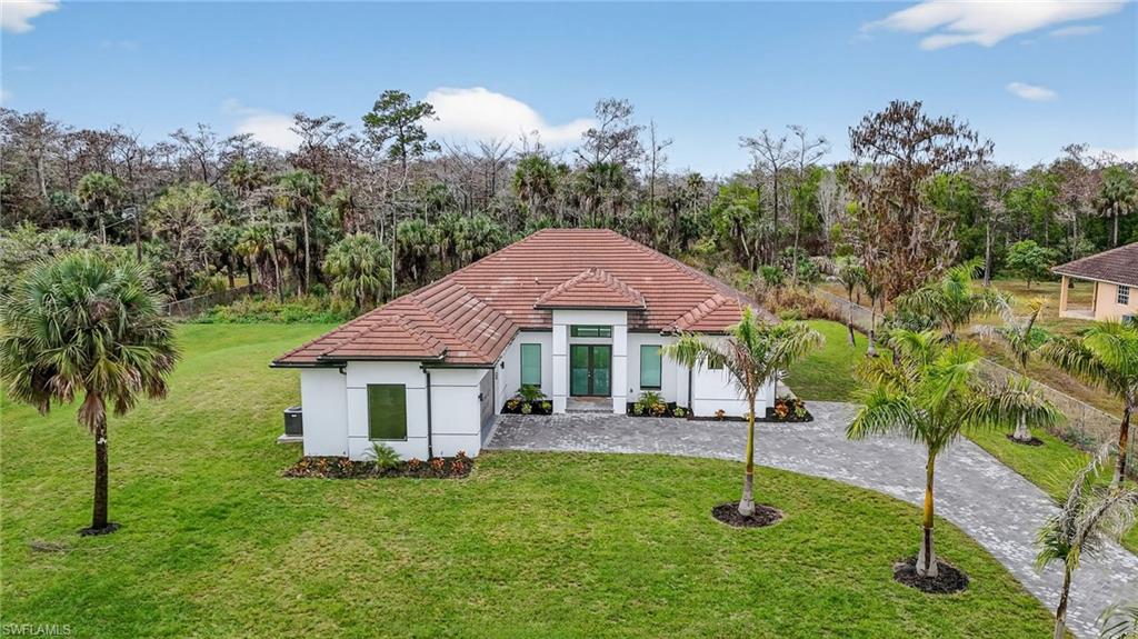 563 15th Street Northwest Naples, FL 34120 - Photo 4 of 33 Rear view of property featuring a yard, french doors, stucco siding, decorative driveway, and a tile roof